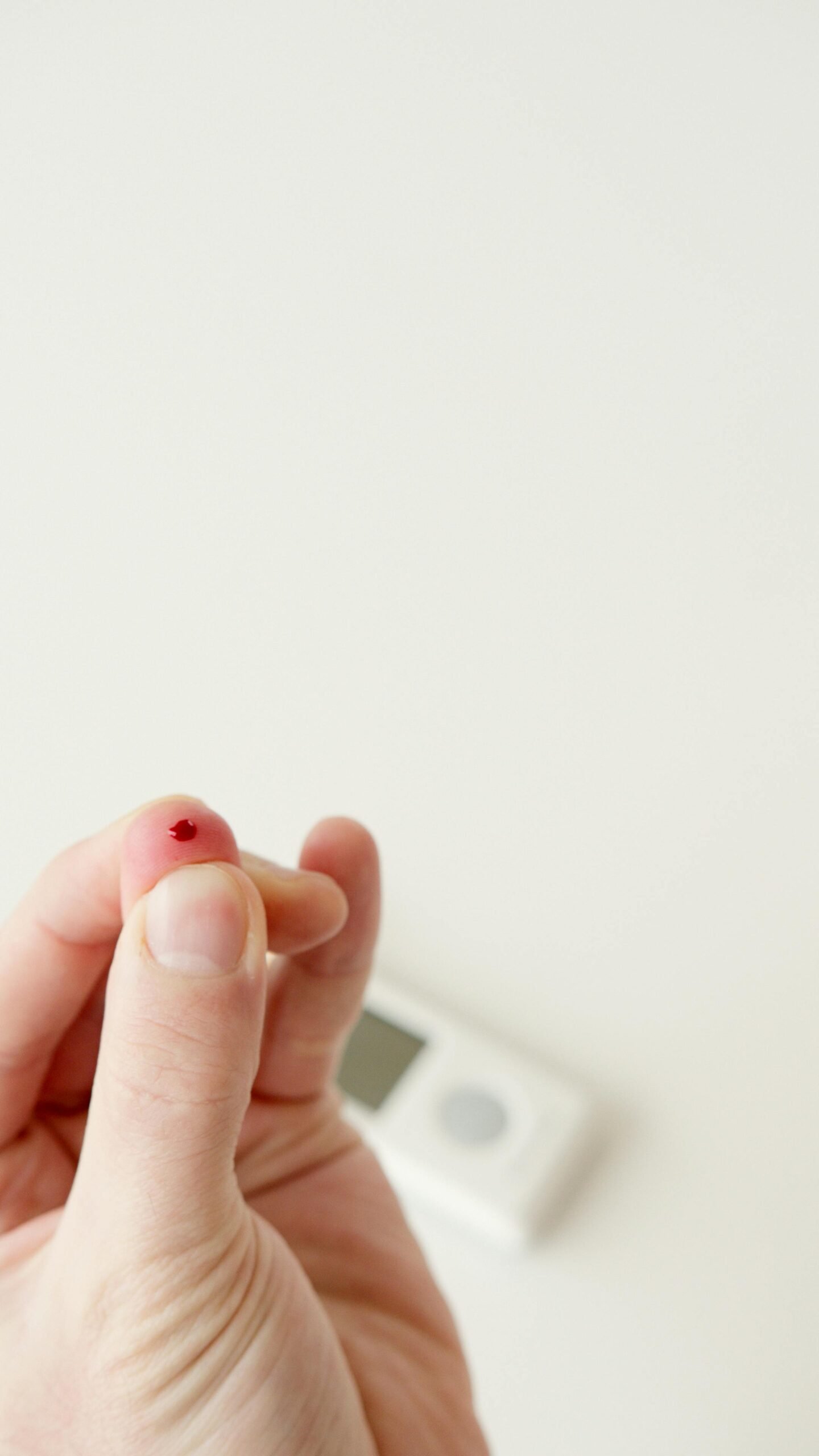 Close-up image of a finger prick with visible blood drop, used for diabetes blood sugar monitoring at home.